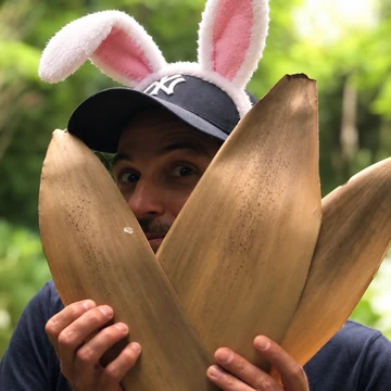 Paul wearing bunny ears, peeking between big leaves